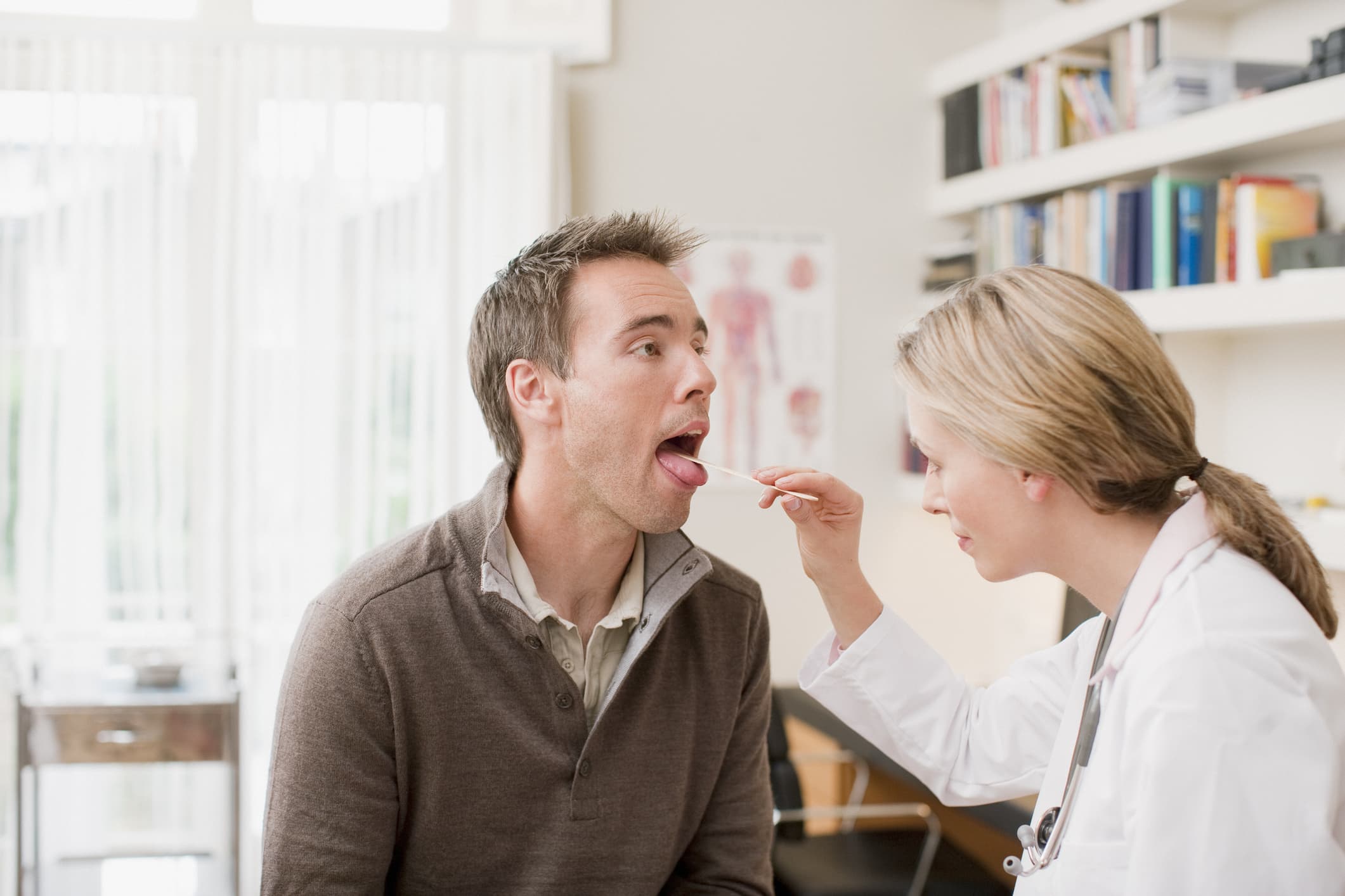Doctor examining patients throat in doctors office